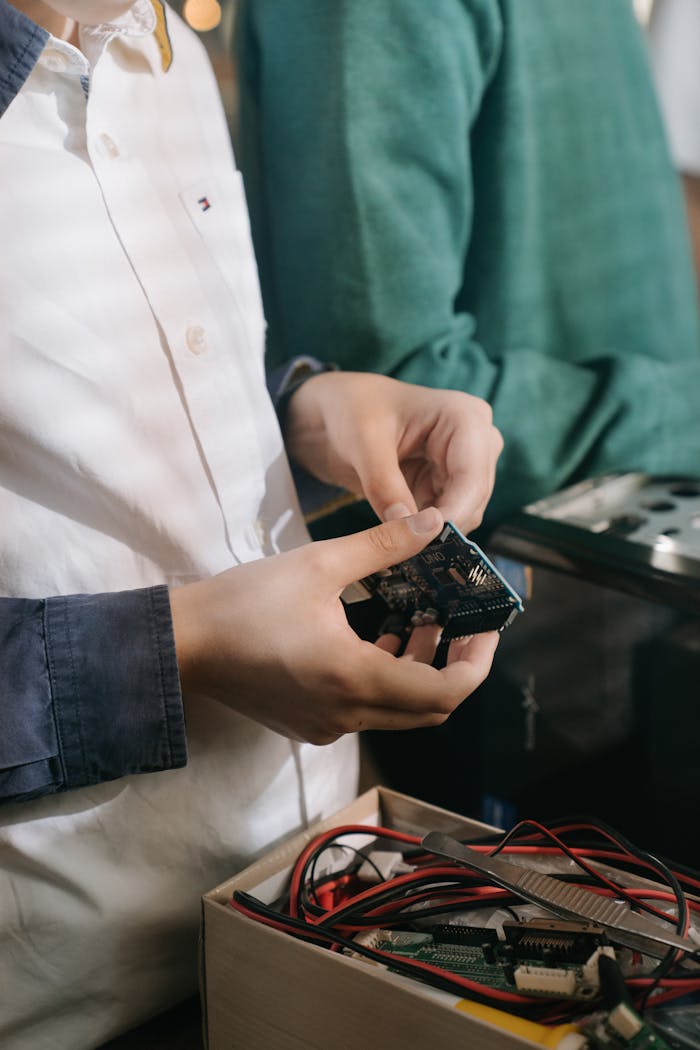 Close-up of a person handling a microchip while working on an electronics project indoors.