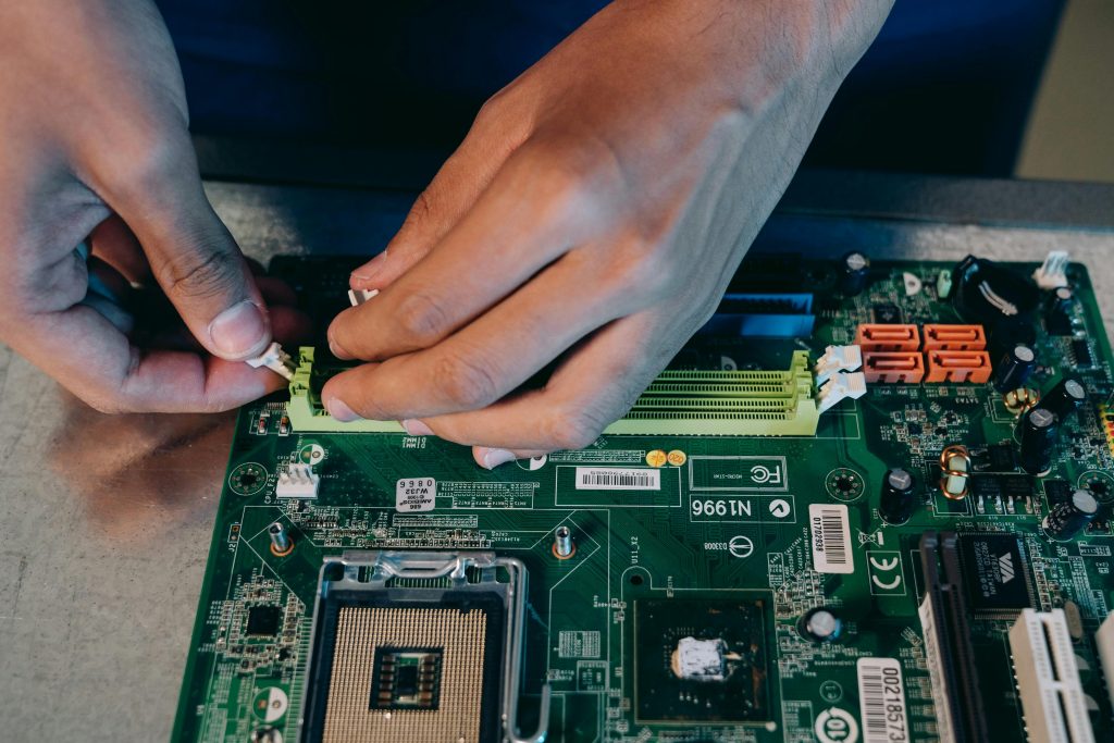 Hands carefully assembling a computer motherboard, showcasing technical craftsmanship in electronics.