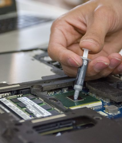 Technician working on hardware inside an opened laptop