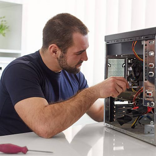 Young man repairing computer while sitting at his working place